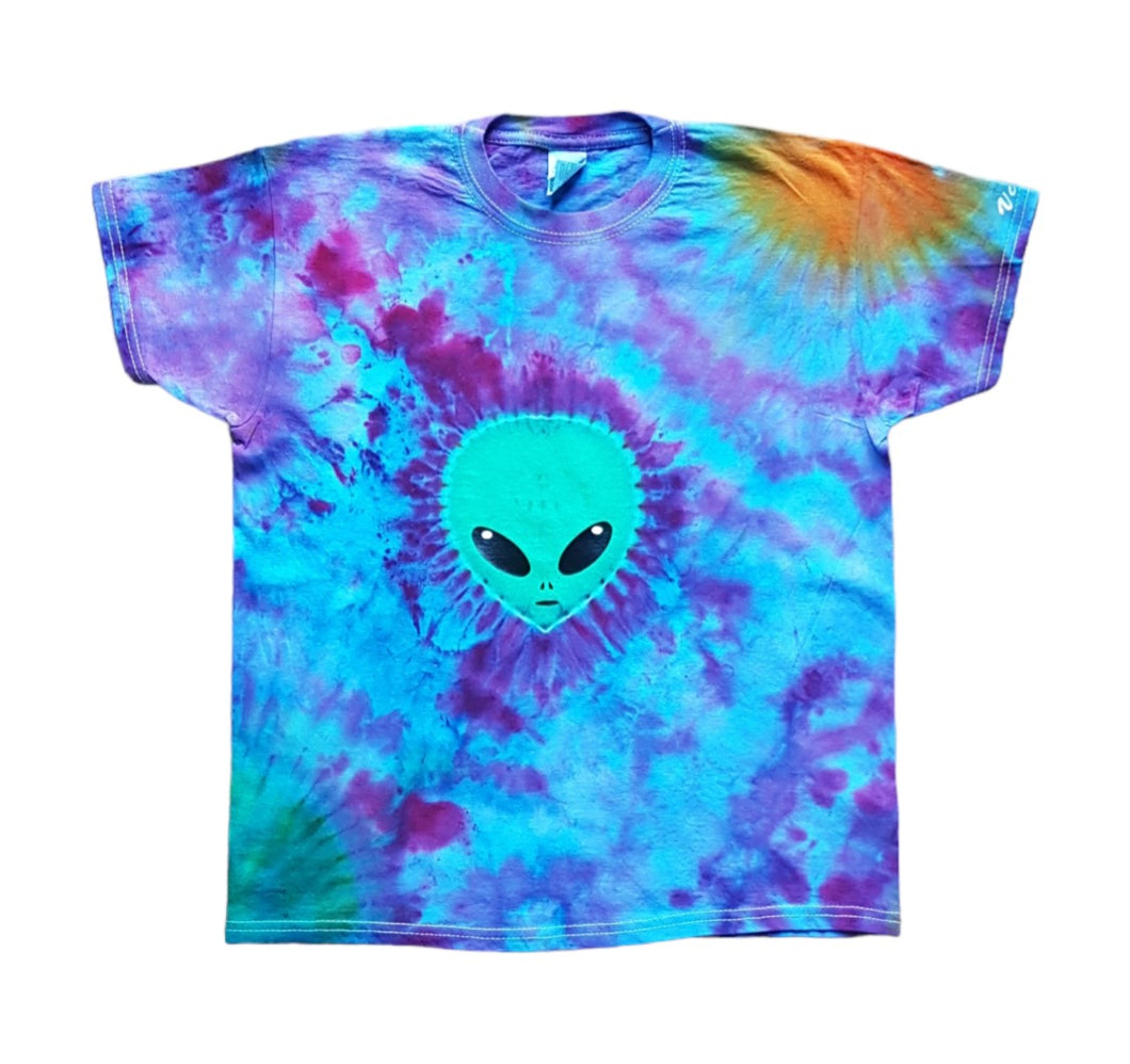 Halloween Alien face and planets tie dye shirt. Alien face is green and in the centre of the shirt with a green planet at bottom left of the shirt and an orange planet at top right of the shirt. The remaining colour of the shirt is a mix of purple and blue hues.