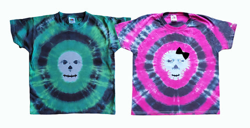 Halloween Skull design tie dye short sleeve shirts. The Skull face is centre of the shirt. The left shirt is green & black and the right shirt is pink and black with an added bow.  