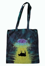 Load image into Gallery viewer, Halloween Cow being abducted by a UFO design tie dye tote bag. Overall colour of the bag is Blue with a black Cow upside down under a UFO shining yellow light