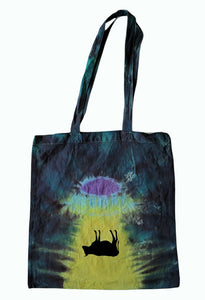 Halloween Cow being abducted by a UFO design tie dye tote bag. Overall colour of the bag is Blue with a black Cow upside down under a UFO shining yellow light