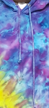 Load image into Gallery viewer, Ice tie dyed Northern Lights inspired hoodie. Overall blue and purple colour scheme with a lime green band diagonal from bottom left to right shoulder. Close up of the drawstrings
